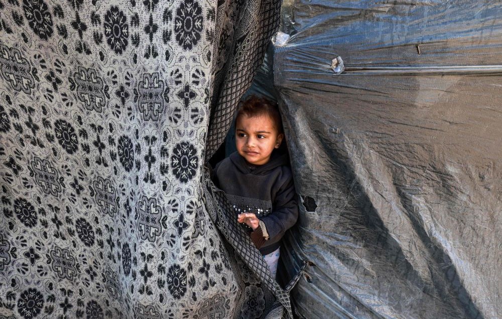 A child peeks out of a tent sheltering displaced Palestinians in Rafah, southern Gaza Strip, Feb. 8, 2024. (AFP)