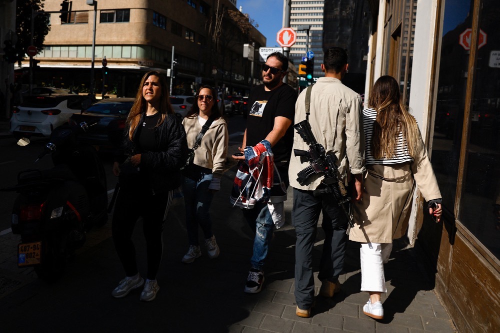 People walk past an off-duty Israeli soldier carrying an assault rifle, amid the ongoing conflict between Israel and Hamas, in Tel Aviv, Israel February 9, 2024. (Reuters)