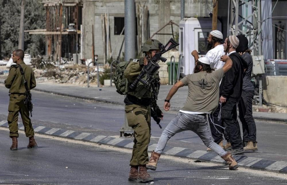 Israeli soldiers stand by as Israeli settlers throw stones at Palestinians during clashes in the town of Huwara in the West Bank, Oct. 13, 2022. (AFP)