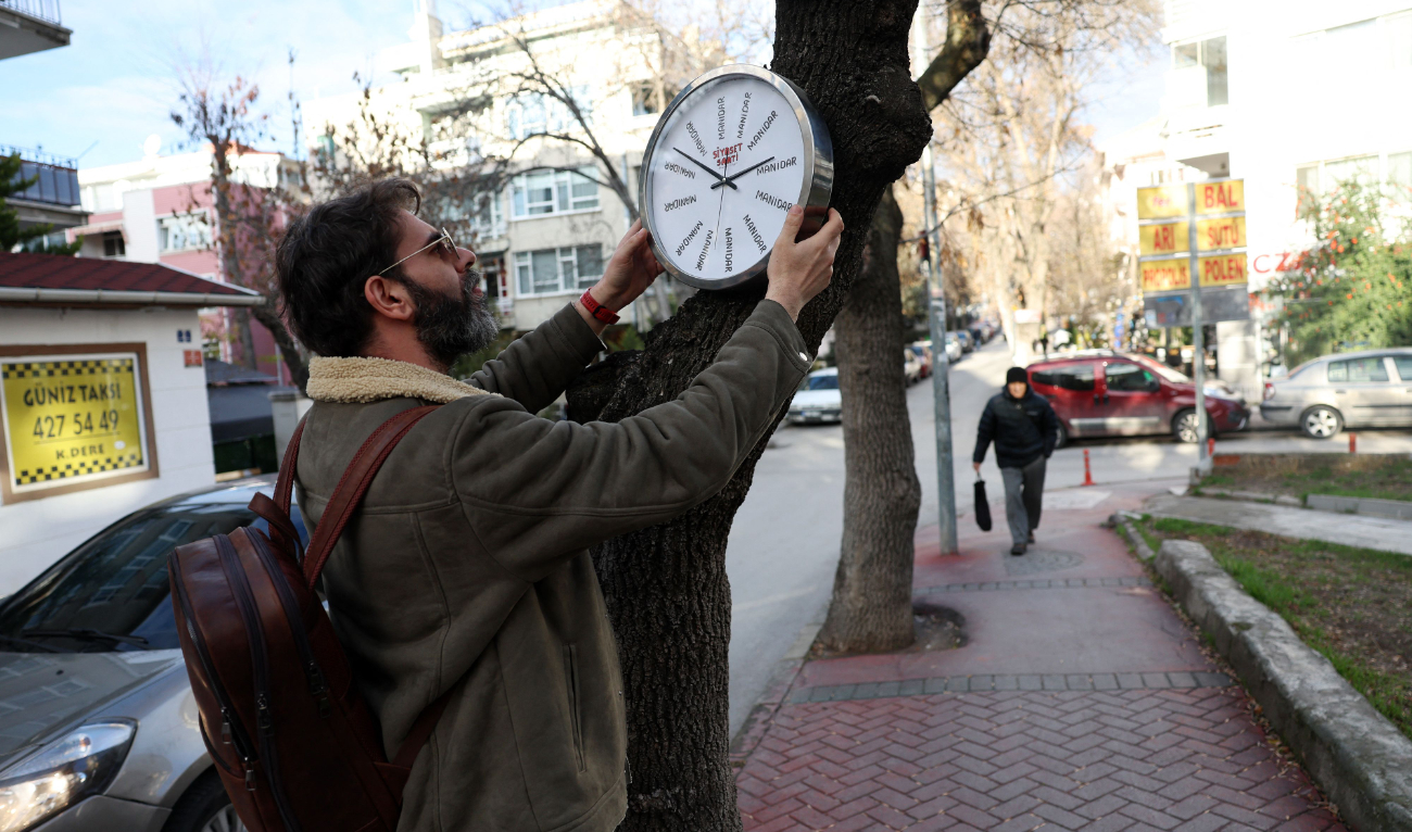 Turkish street artist Hikmeti Tabiyeci installs one of his creations titled ‘political clock’ on a tree on a street in Ankara. (AFP)