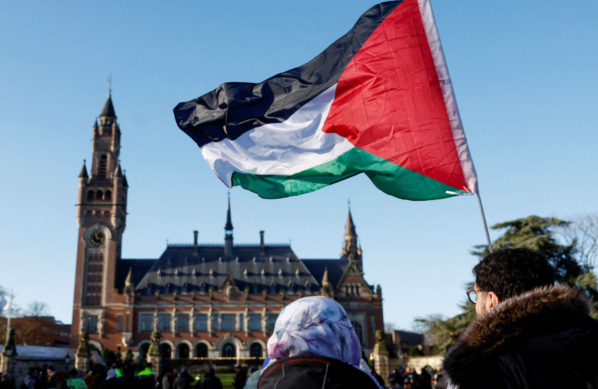 Protesters hold a Palestinian flag as they gather outside the International Court of Justice (ICJ) as judges rule on emergency measures against Israel following accusations by South Africa that the Israeli military operation in Gaza is a state-led genocide, in The Hague, Netherlands, January 26, 2024. (REUTERS)