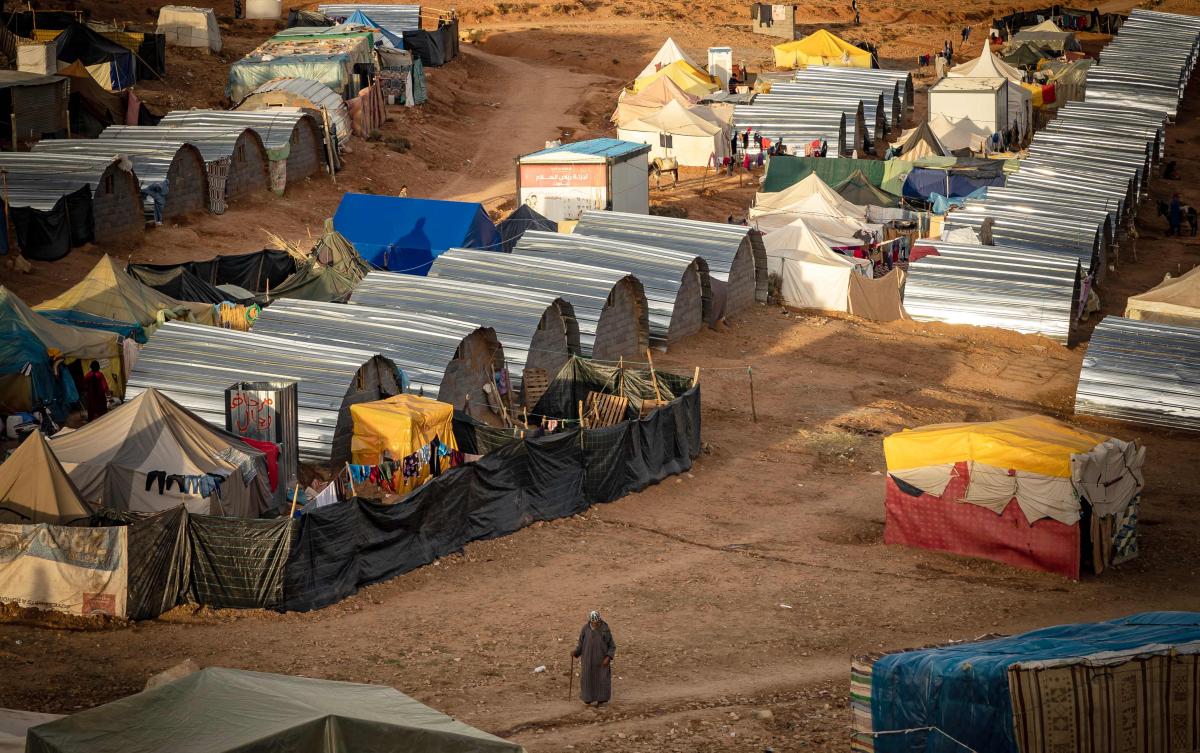 A man walks past huts built by Moroccan and Dutch NGOs at a camp near the earthquake-hit village of Douzrou, in central Morocco on Feb. 13, 2024. (AFP)