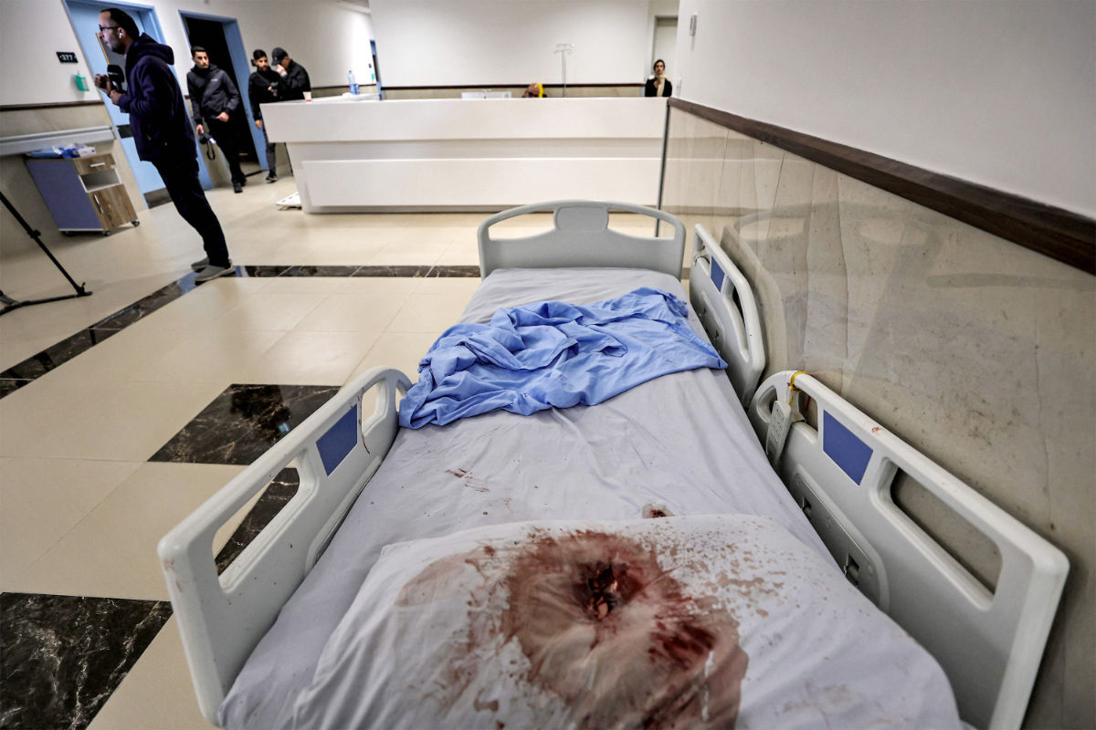 Journalists film near a hospital bed with a blood-stained pillow with a visible bullet hole at the Ibn Sina hospital in Jenin in the occupied West Bank on January 30, 2024. (AFP)