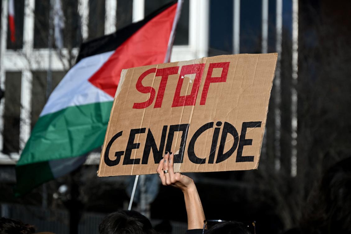 Demonstartors, one holding a placard and anothers the Palestinian flag during a 'Protest for Palestine' and in front of the Italian national television headquarter RAI, in central Rome on February 17, 2024. (AFP)