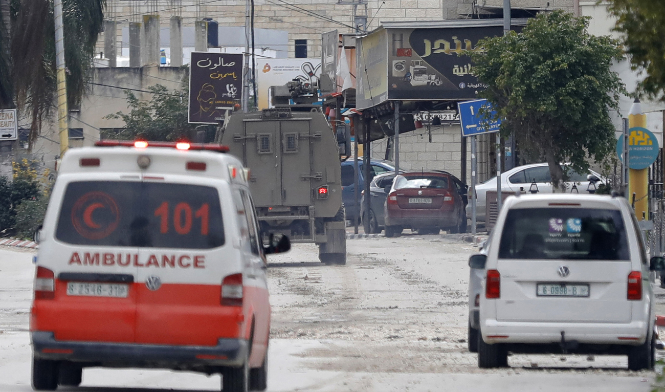 A Red Crescent ambulance enters as Israeli military vehicles retreat after a raid on the Tulkarm camp for Palestinian refugees in the occupied West Bank on February 18, 2024. (AFP)