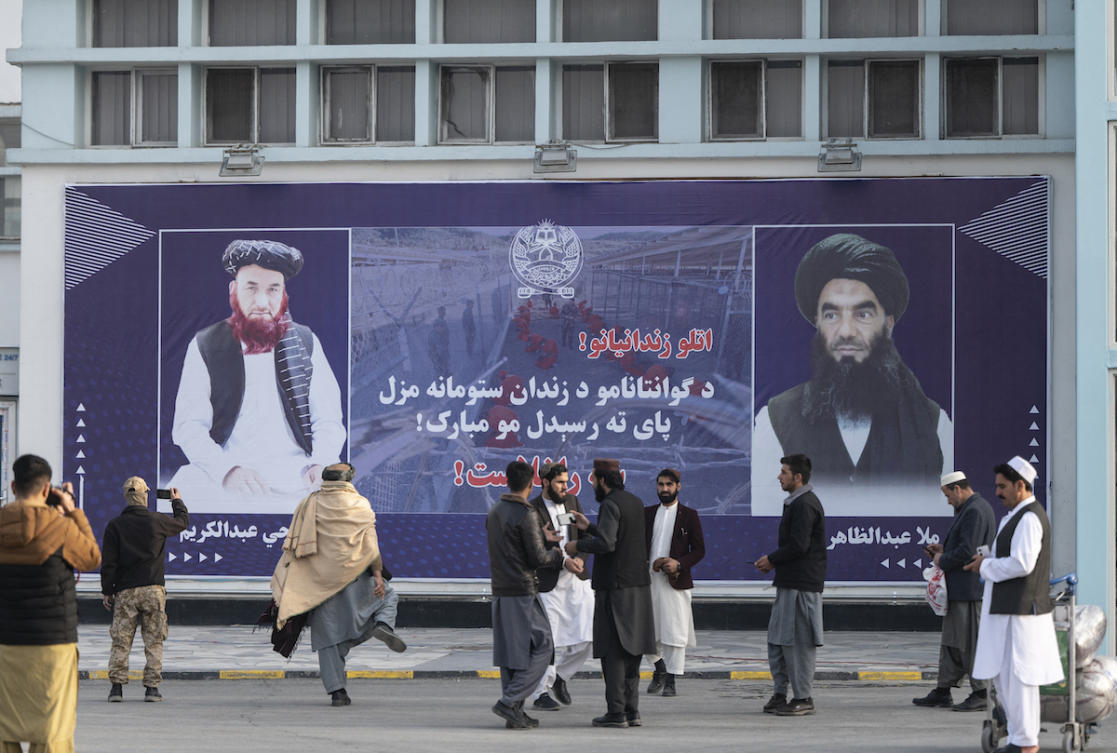 Afghan men stand next to a billboard welcoming the two former prisoners held at the US detention centre in Guantanamo Bay. (File/AFP)