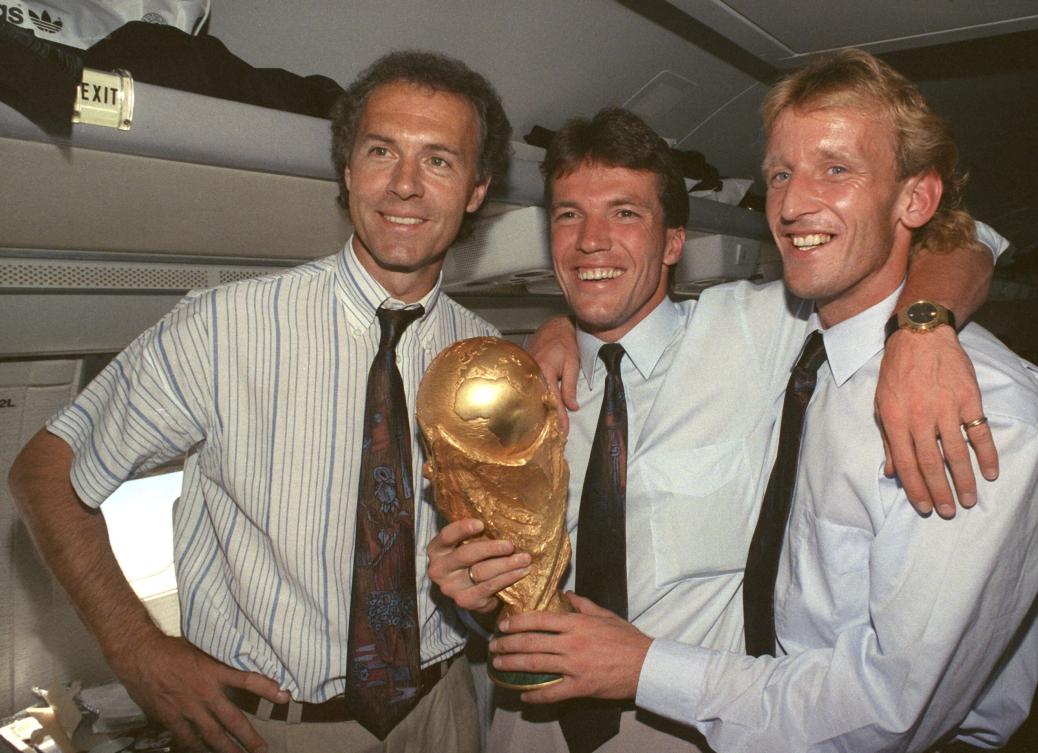 From left, Germany national soccer team’s Franz Beckenbauer, Lothar Matthaeus and Andreas Brehme pose with the World Cup trophy on July 9, 1990. Brehme, who scored the only goal as West Germany beat Argentina to win the 1990 World Cup final, has died. He was 63. (AP)