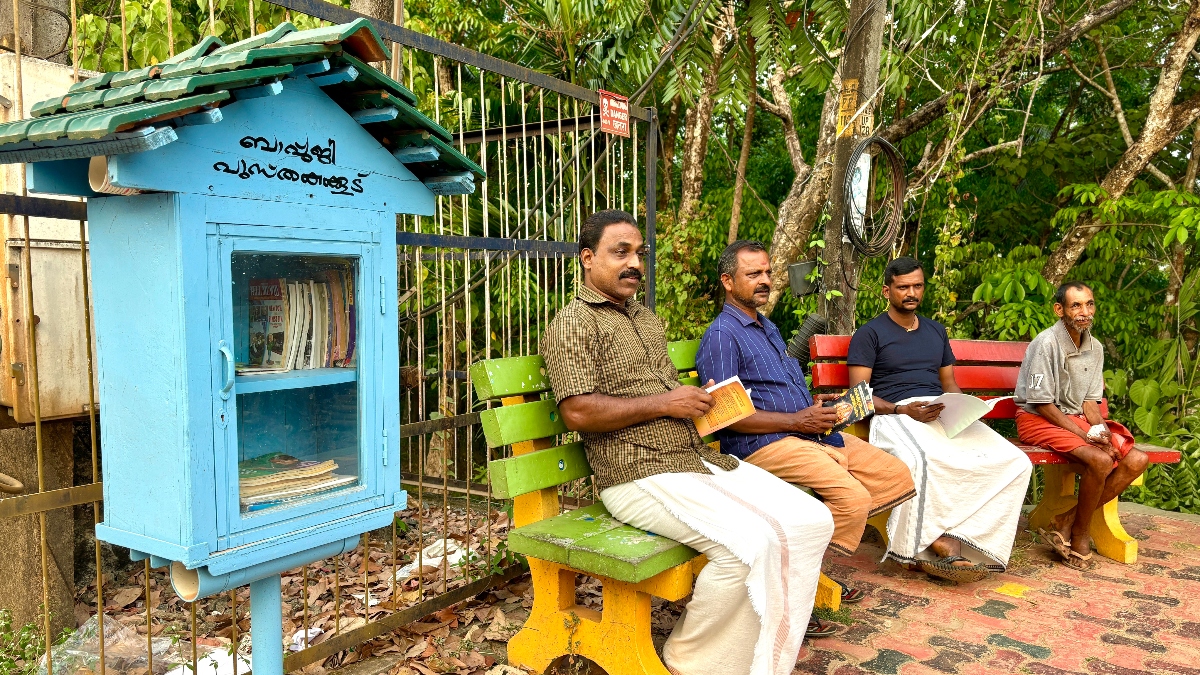 Residents sit and read next to one of the 14 public mini-libraries in Perukulam, Kollam district, India’s Kerala state, February 2024. (V. Vijesh)
