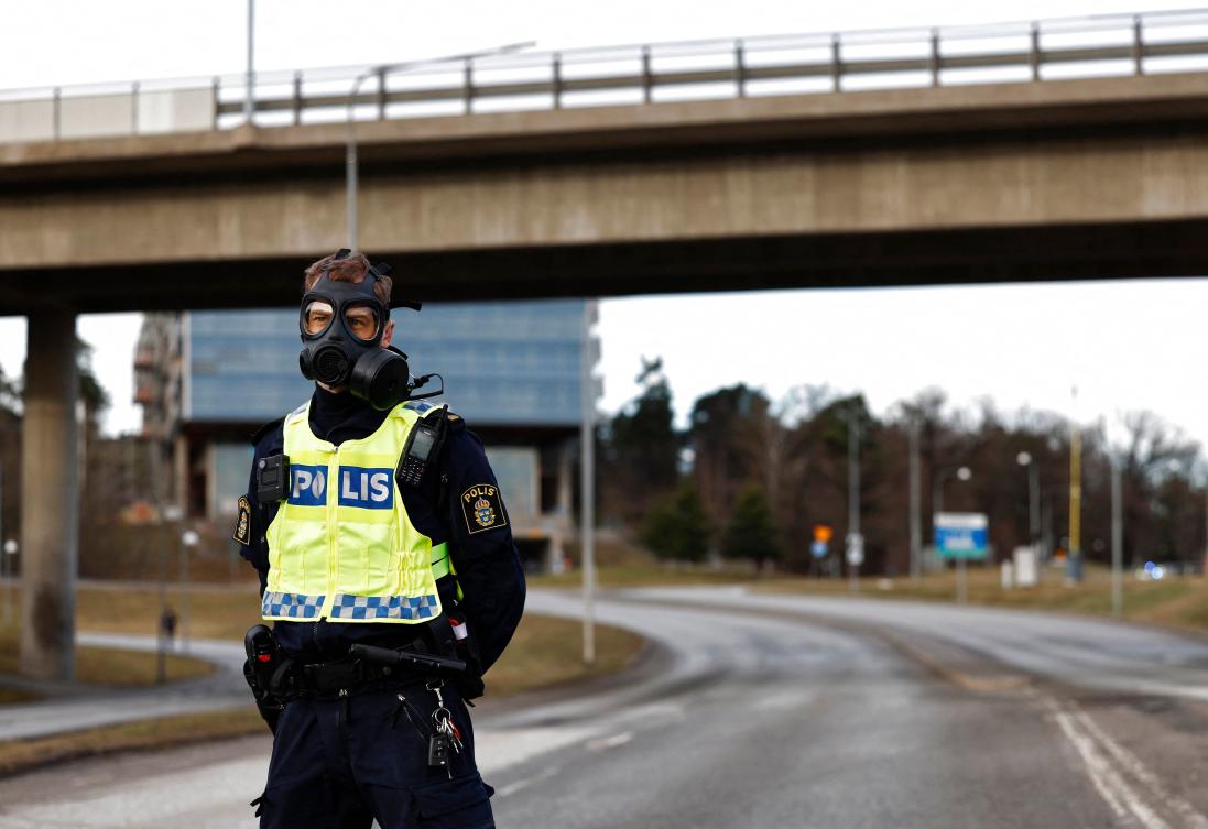 A Police officer wearing a gas mask stands guard at the scene after emergency services were alerted to Sweden’s Security Service’s (Sapo) headquarters in Solna, north of Stockholm, because of a suspected gas leak at the premises on Feb. 23, 2024. (AFP)