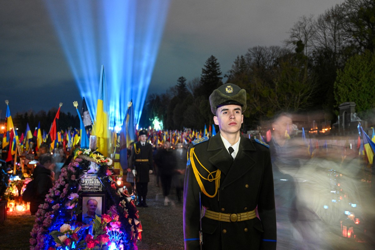Ukrainian honour guards stand as a symbolic illumination called "Ray of Memory" is seen over the graves of Ukrainian soldiers, who died in the war with Russia, at Lychakiv Cemetery in Lviv (AFP)