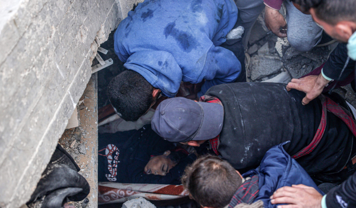 Palestinians evacuate the body of a boy from the rubble of a house destroyed in an overnight Israeli air strike in east Khan Yunis in the southern Gaza Strip on February 26, 2024, amid continuing battles between Israel and the Palestinian militant group Hamas. (AFP)