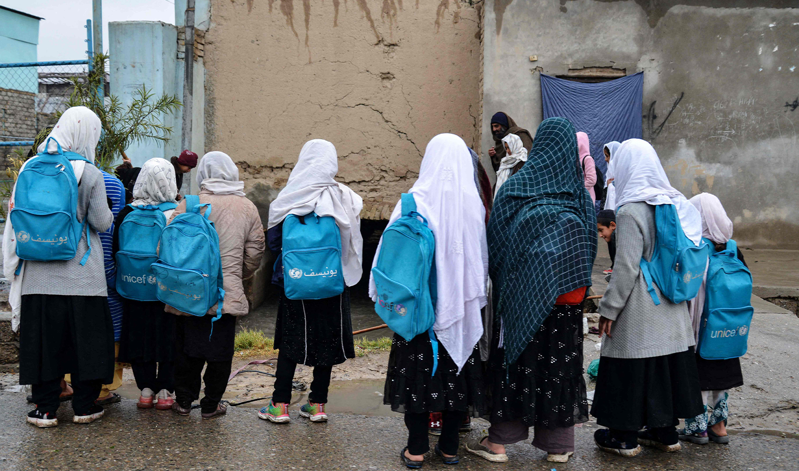 Afghan girl students carrying school bags observe rainwater collected in a canal along a roadside in Kandahar on February 26 2024. (AFP)