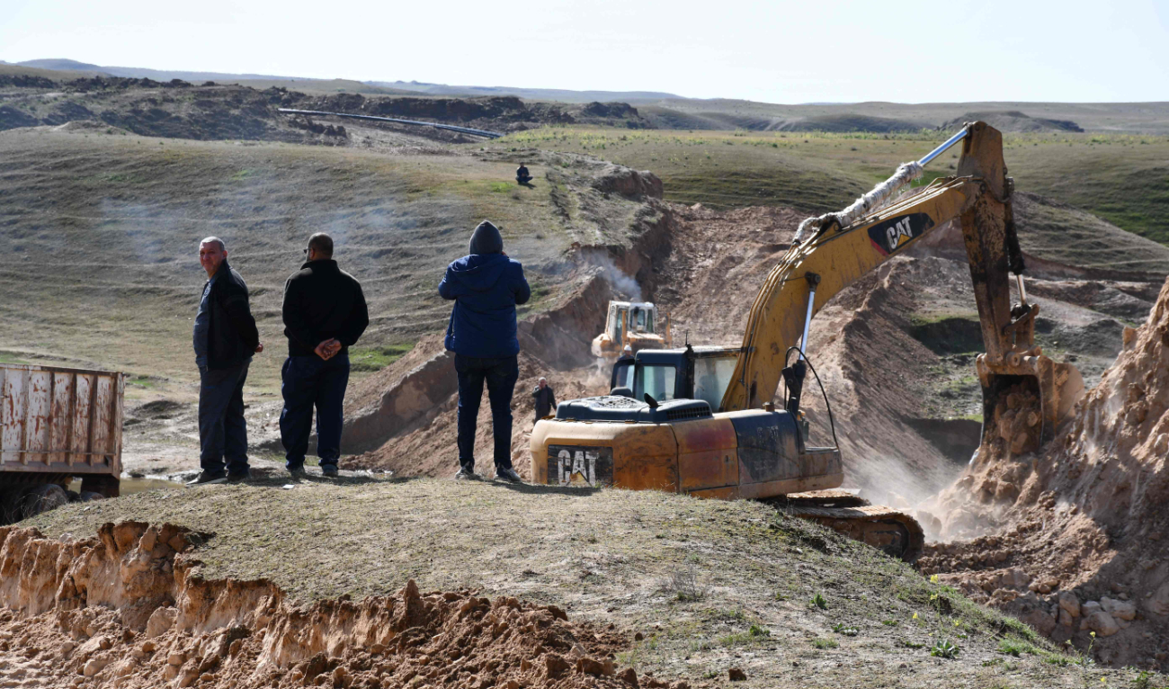 Iraqi farmers watch as excavators build up dirt barriers to stem the flow of contaminated water following an oil spill on agricultural land in Hamrin, north of Tikrit, Iraq. (AFP)