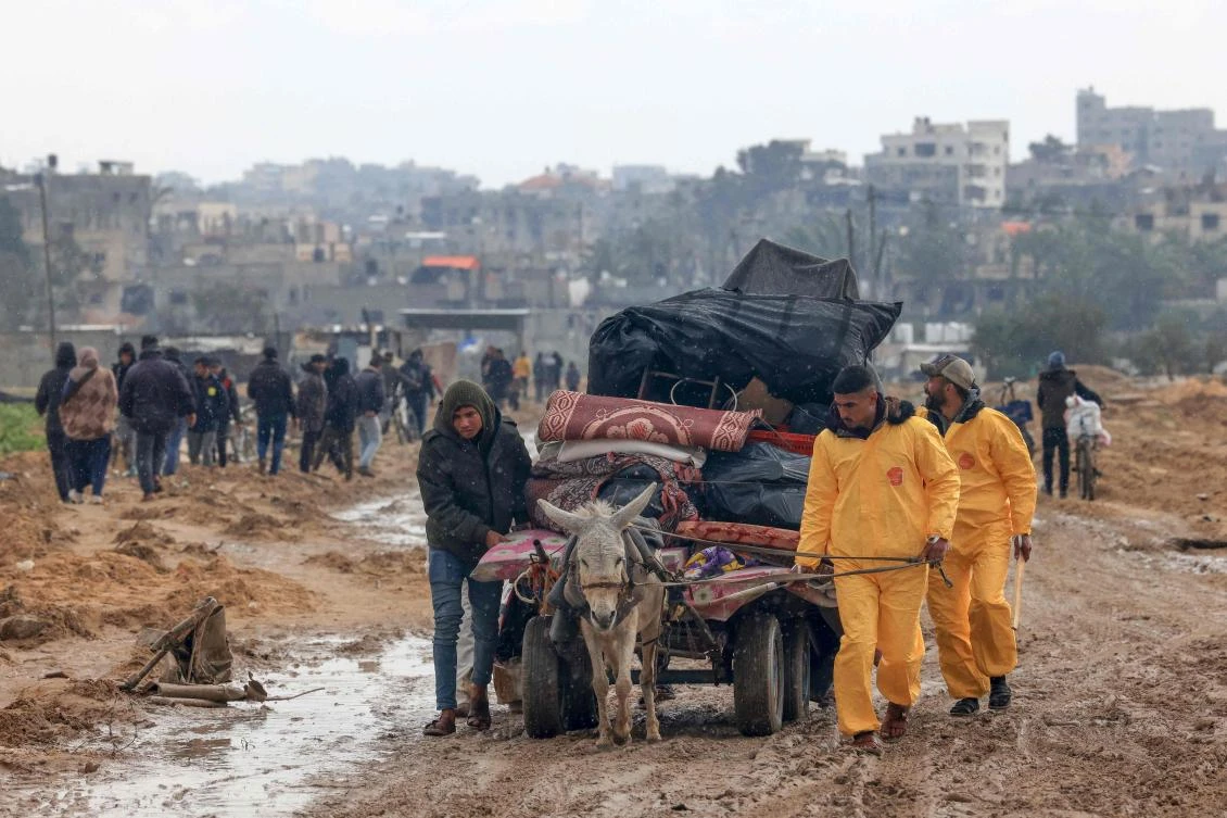 Palestinians, some wearing Hazmat suits left over from the Coronavirus pandemic to keep warm, transport some of their belongings as the flee Khan Yunis in the southern Gaza Strip further south on Feb. 2, 2024. (AFP)