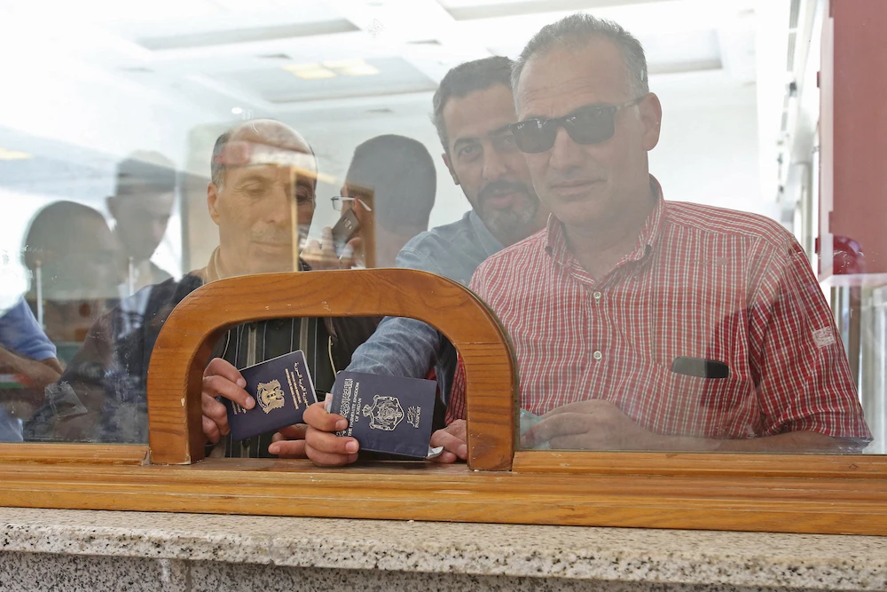 Jordanian travelers show their passports at the Jaber border crossing between Jordan and Syria. (File/AFP)