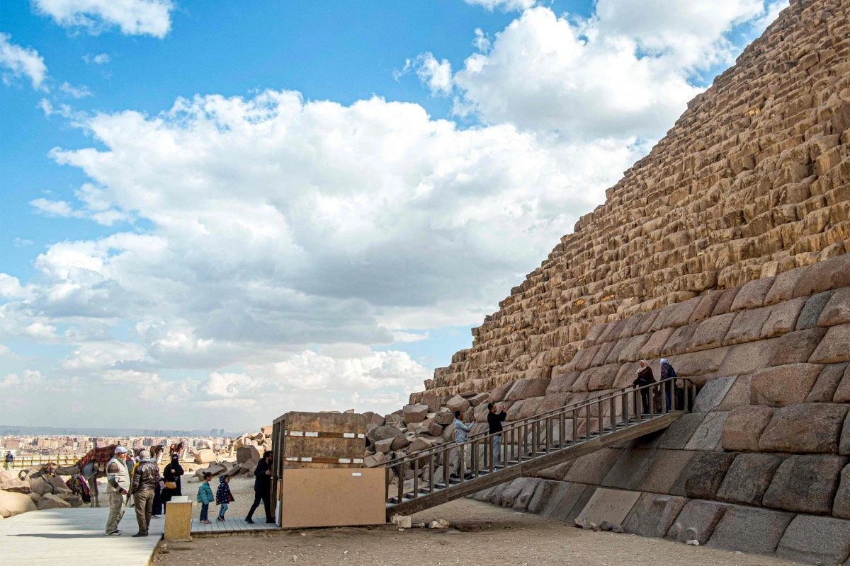 Visitors pose for a picture by the base of the Pyramid of Menkaure (or Menkheres, built in the 26th century BC) at the Giza Pyramids Necropolis, west of Cairo, on January 29, 2023. (AFP)
