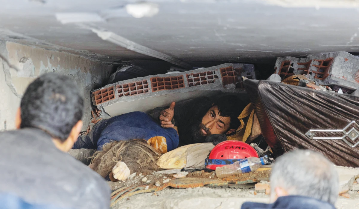 Abdulalim Muaini looks out from under rubble as his wife lies dead next to him in the aftermath of a deadly earthquake in Hatay, Turkey, on February 8, 2023. The quake left millions homeless. (Reuters)
