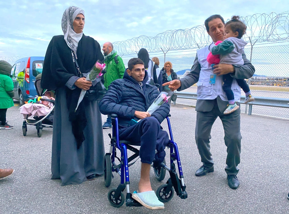 Geneva-based doctor Raouf Salti holds 17-month-old Zeina, next to 16-year-old Yussef and his mother who were evacuated from Gaza to Switzerland to receive medical treatment, at their arrival at Geneva airport, on Feb. 12, 2024. (Reuters)