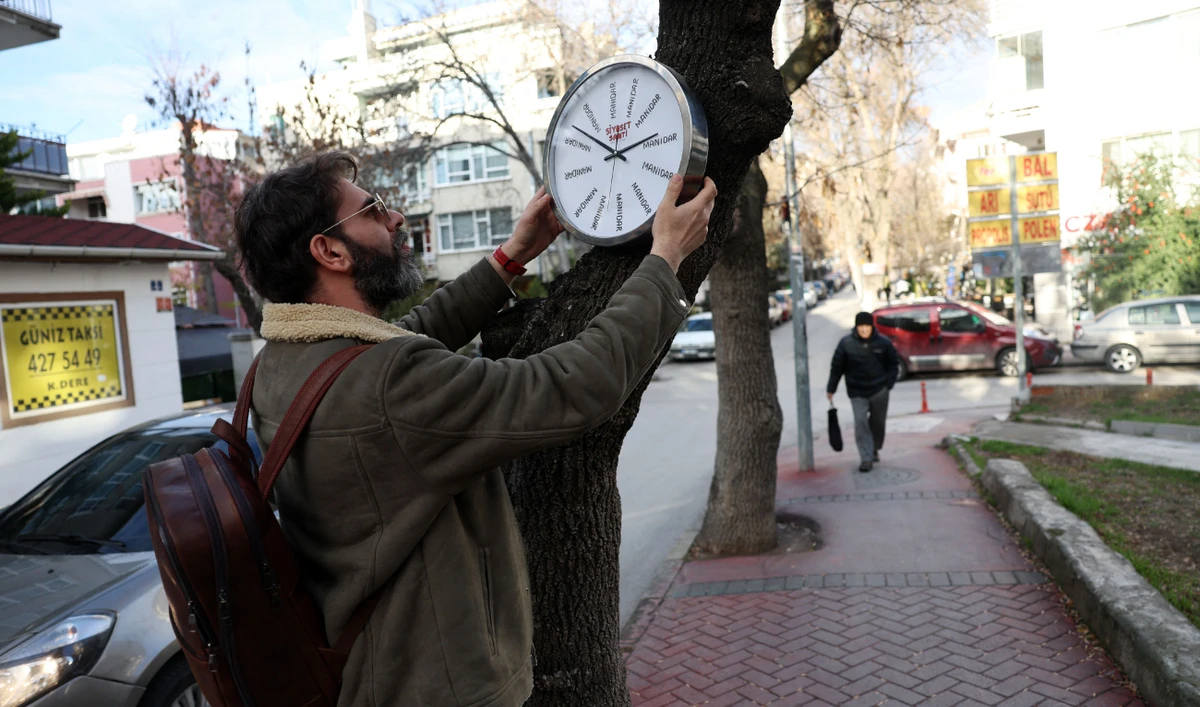 Turkish street artist Hikmeti Tabiyeci installs one of his creations titled ‘political clock’ on a tree on a street in Ankara. (AFP)