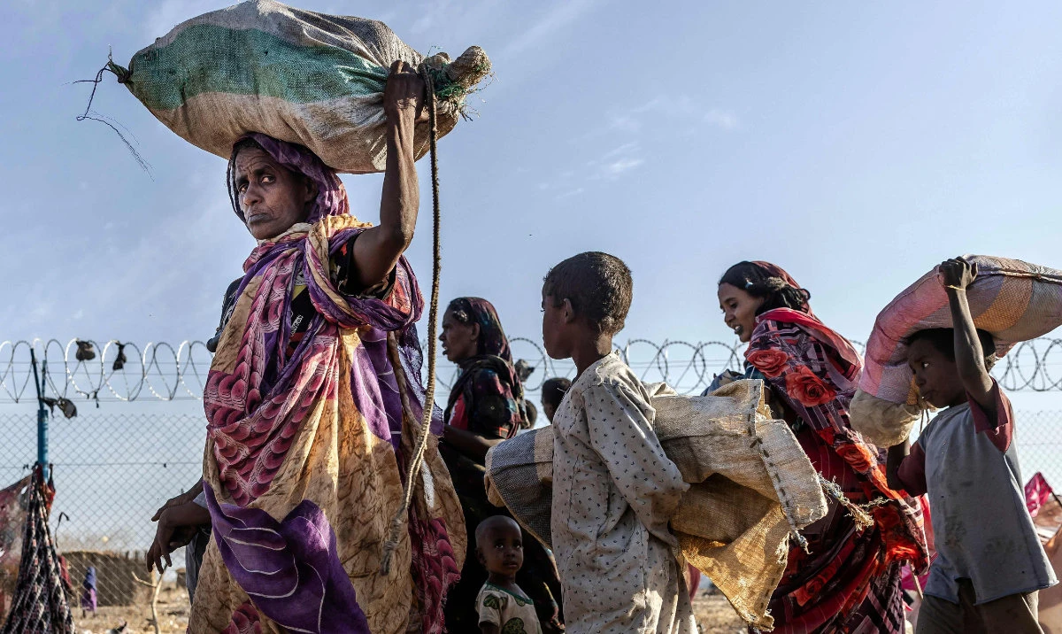 Sudanese families who have fled from the war in Sudan carry their belongings while arriving at a Transit Centre for refugees in Renk, on February 14, 2024. (AFP)