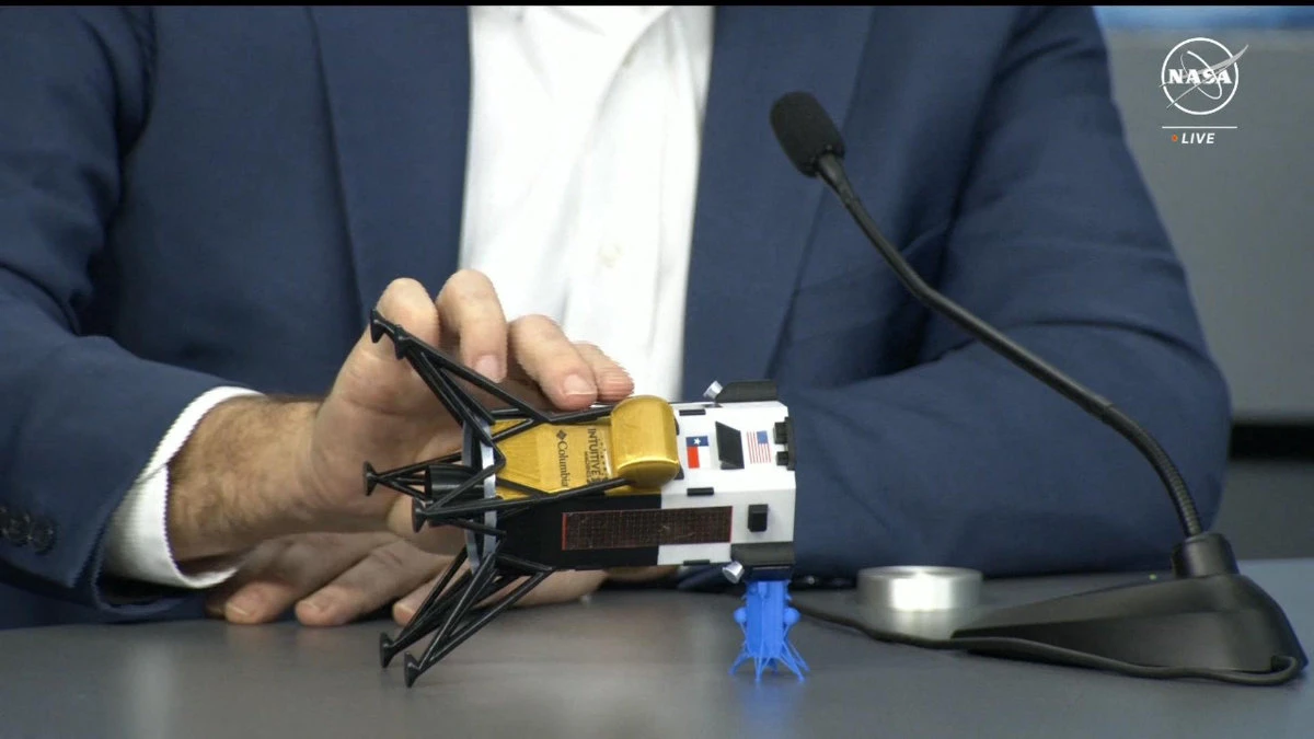 This frame grab from NASA, shows Intuitive Machines CEO Steve Altemus holding a model of Odysseus to show its position on the side during a press conference at Johnson Space Center in Houston, Texas on February 23, 2024. (Handout / NASA TV via AFP)