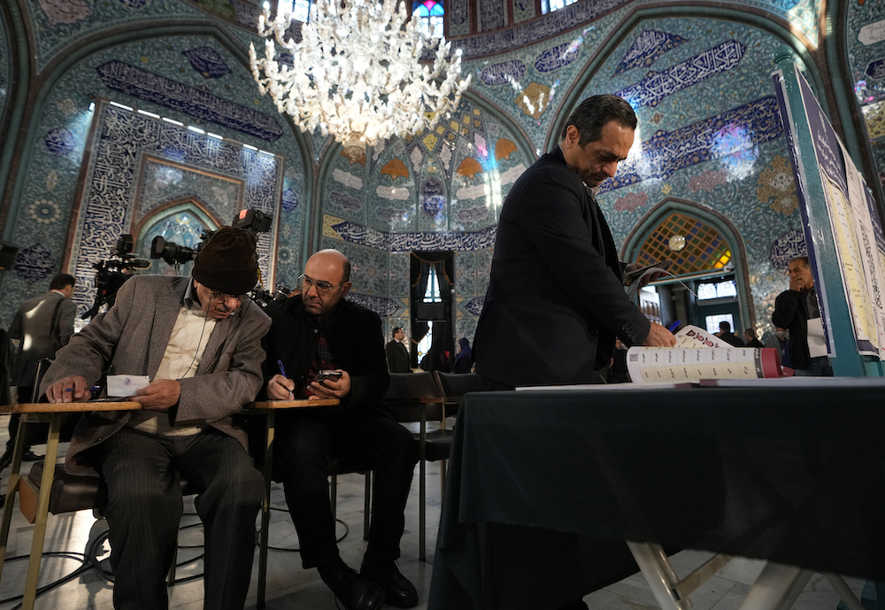 Voters fill out their ballots in the parliamentary and assembly of experts elections at a polling station in Tehran on March 1, 2024. (AP)