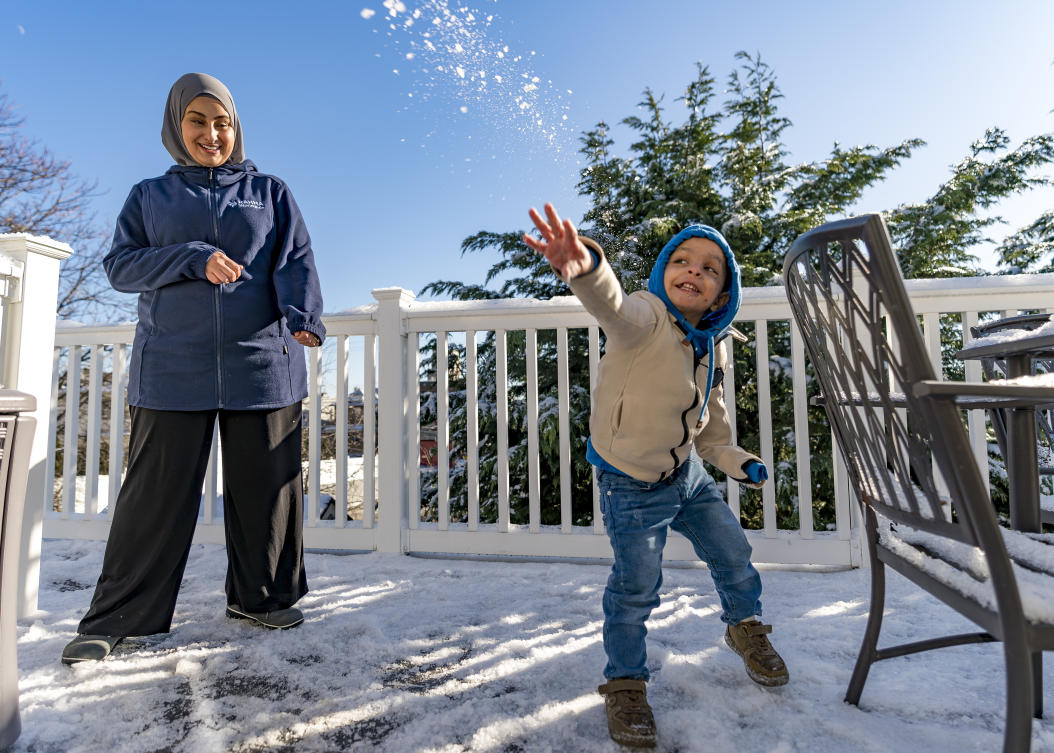 Omar Abu Kuwaik, throws snow shortly after arriving from Gaza at the residence of the Global Medical Relief Fund as Khaolah Obahi of Rahma Worldwide looks on, Wednesday, Jan. 17, 2024 (AP)