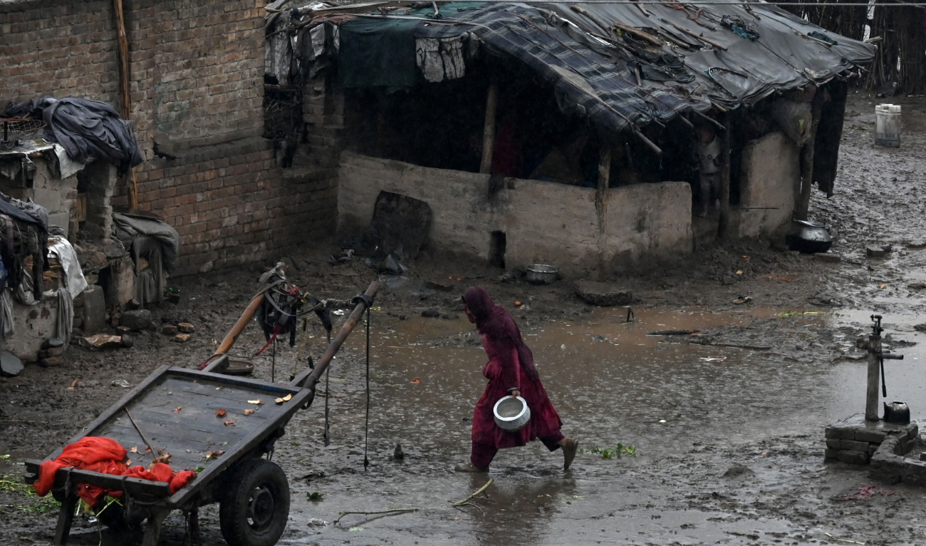 A woman runs towards a shade amid a drizzle in Peshawar on March 1, 2024. (AFP)