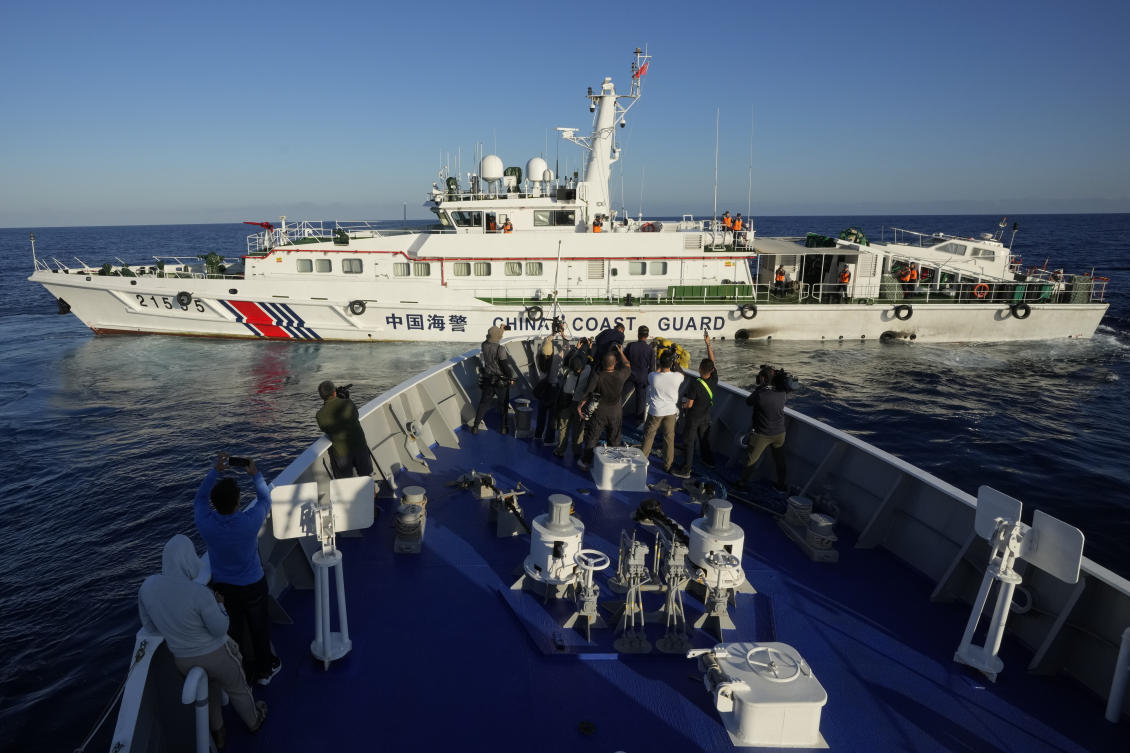 Journalists report as a Chinese coast guard ship blocks the path of Philippine coast guard BRP Sindangan as they try to enter the Second Thomas Shoal, locally known as Ayungin Shoal, in the disputed South China Sea on March 5, 2024. (AP)