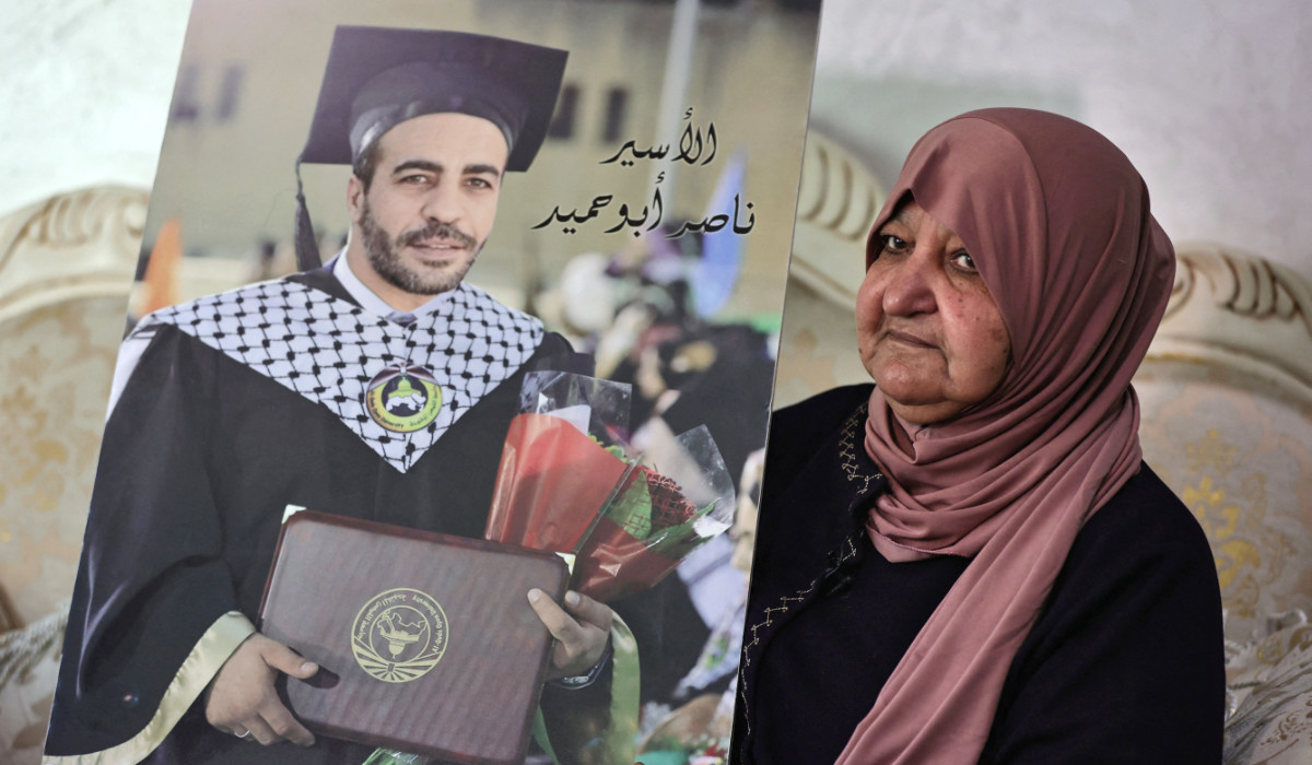 Palestinian Latifa Abu Hamid, 74, holds a portrait of one of her children, at her house in Ramallah, in the occupied West Bank, on February 29, 2024. (AFP)