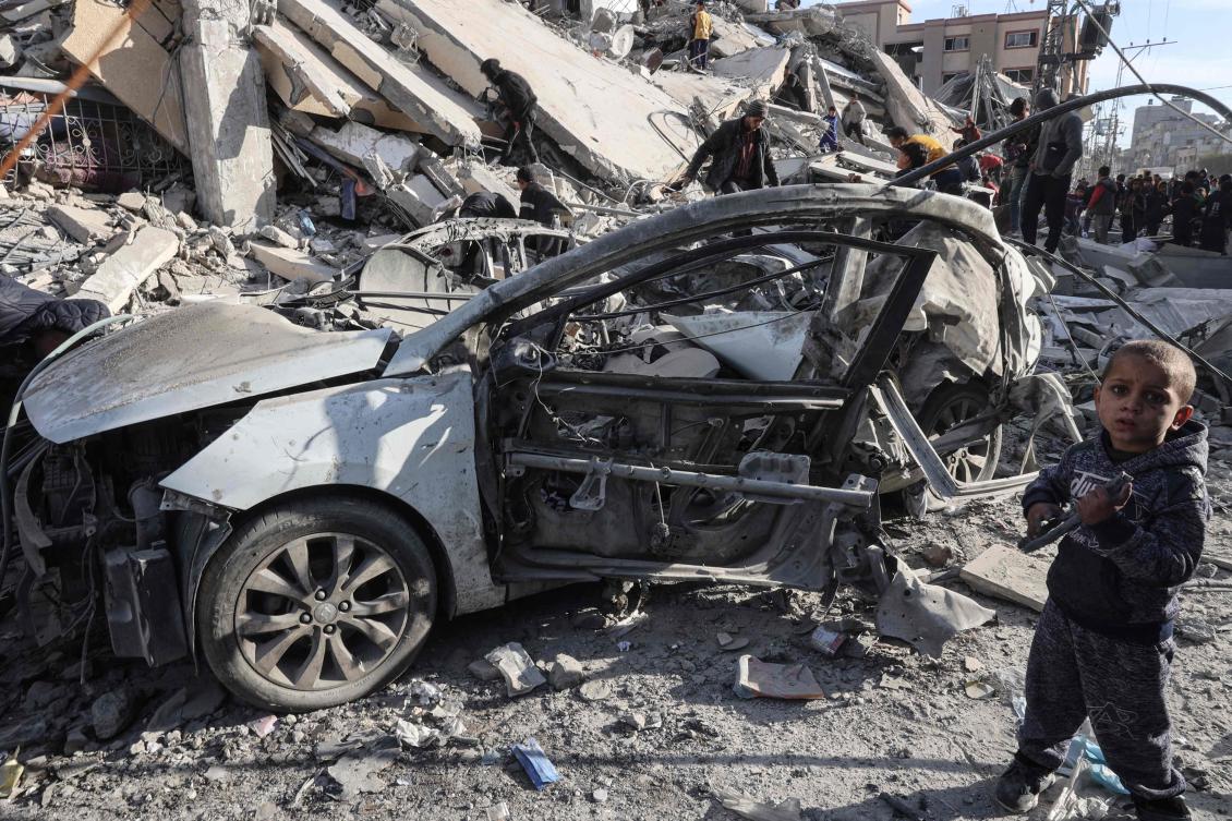 A young Palestinian boy stands next to a wrecked car in the rubble of a residential building hit in an overnight Israeli air strike in Rafah in the southern Gaza Strip on March 9, 2023. (AFP)