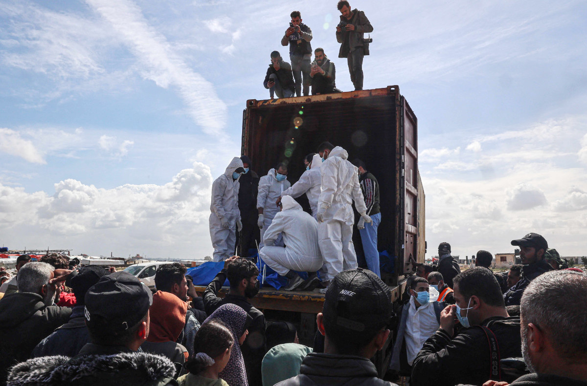 Mourners watch as medical personnel transport the bodies of 47 Palestinians, that were taken and later released by Israel, during a mass funeral in Rafah in the southern Gaza Strip on March 7, 2024, amid ongoing battles between Israel and the militant group Hamas. (AFP)