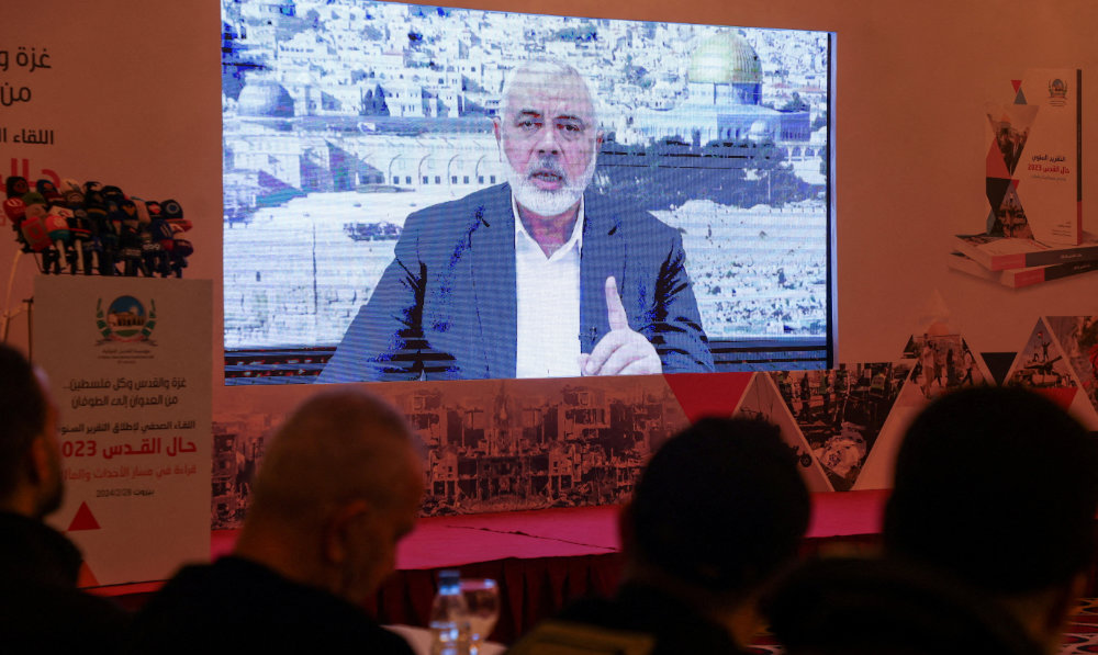 Hamas leader, Ismail Haniyeh, speaks in a pre-recorded message shown on a screen during a press event for Al-Quds International Institution in Beirut, Lebanon February 28, 2024. (Reuters)