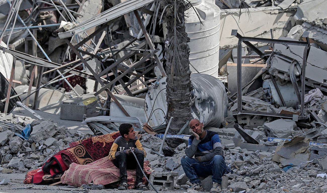 Displaced Palestinians sit with their belongings amid the rubble of houses destroyed by Israeli bombardment in Hamad area, west of Khan Yunis in the southern Gaza Strip on March 14, 2024. (AFP)