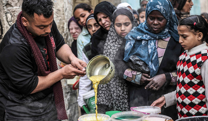 Displaced Palestinians queue to receive food donated by a charity organisation ahead of the fast-breaking "iftar" meal during the Muslim holy month of Ramadan, in Rafah in the southern Gaza Strip on March 16, 2024, amid the ongoing conflict in the Palestinian territory between Israel and the militant group Hamas. (AFP)