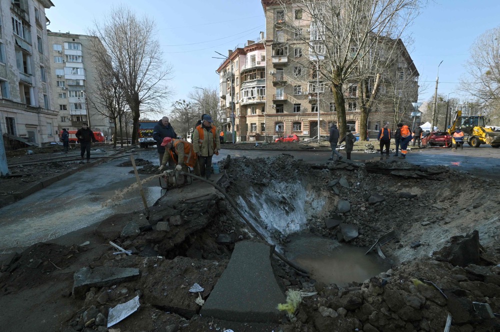 Ukranian municipal services workers survey and repair the damage following a missile attack in Kyiv. (AFP)