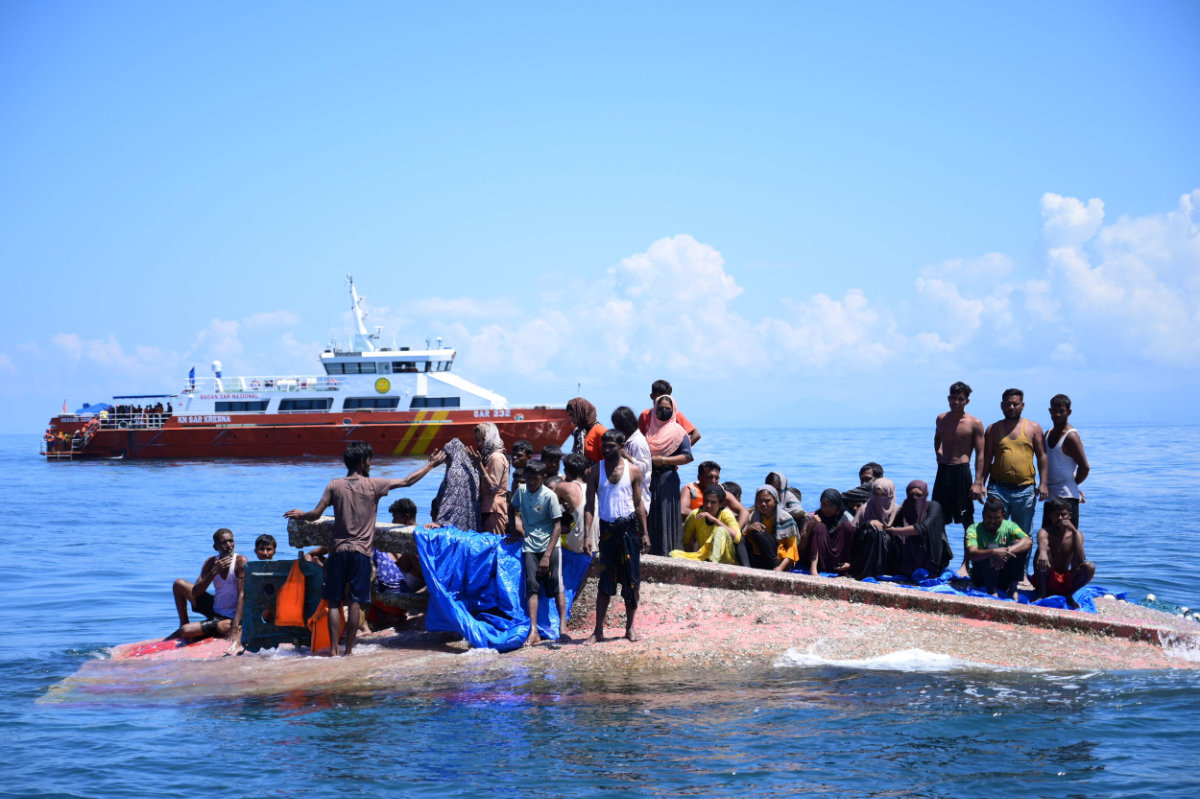Rohingya refugees wait to be rescued from the hull of their capsized boat as an Indonesian rescue vessel approaches in waters some 29 kilometers off west Aceh on March 21, 2024. (AFP)