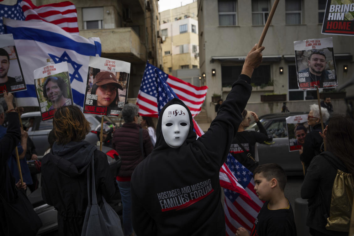 Families and supporters of Israeli hostages held by Hamas in Gaza wave photos of their loved ones and the Israeli and U.S. flags during a protest calling for their return, outside a meeting between U.S. Secretary of State Antony Blinken and families of hostages, in Tel Aviv, on Mar. 22, 2024. (AP)