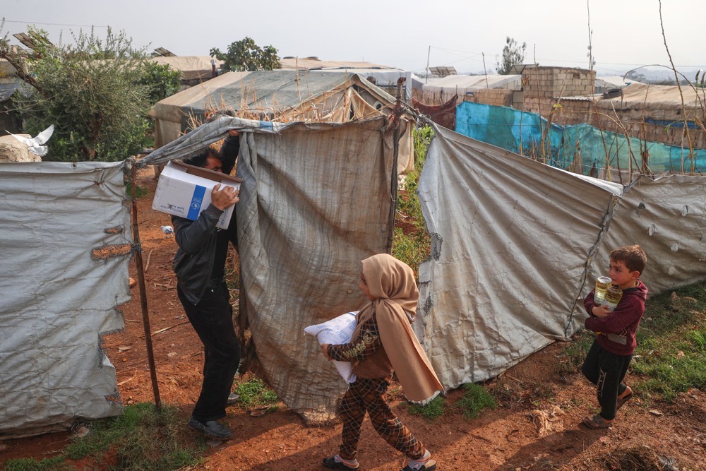 A displaced Syrian family carries relief packages from the United Nations' World Food Program . (AFP)