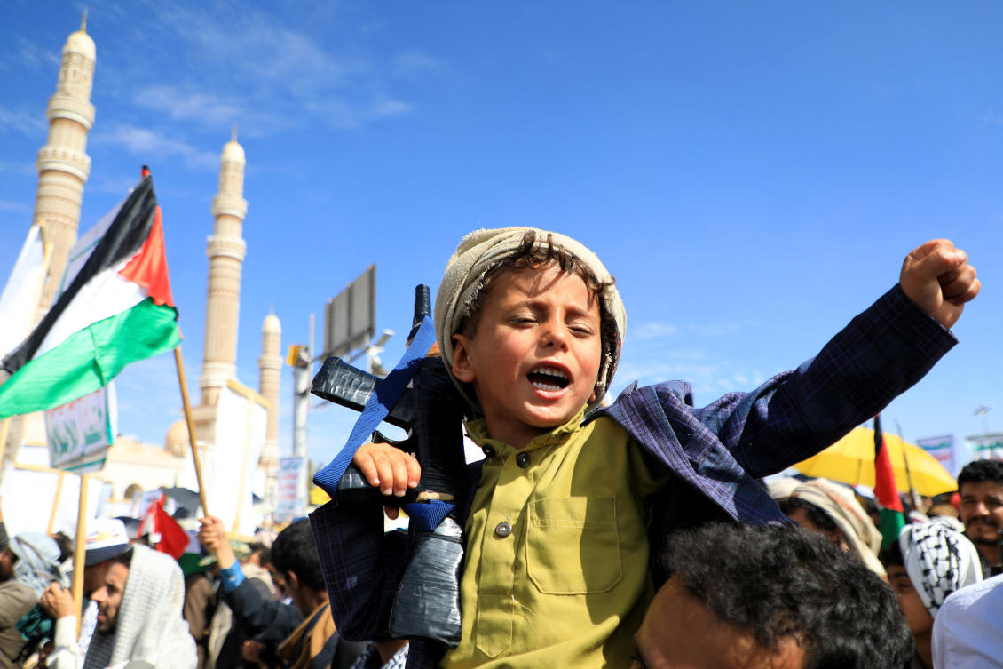 A Yemeni child carries a weapon and chants slogans during a march in the Houthi-run capital Sanaa on March 22, 2024 (AFP)