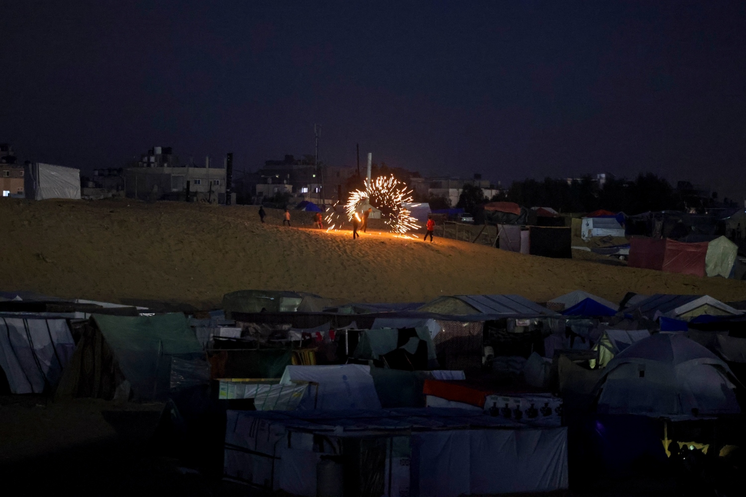 Children play with sparklers at a camp for displaced Palestinians in Rafah on the eve of Ramadan. Mar. 10, 2024 (AFP)