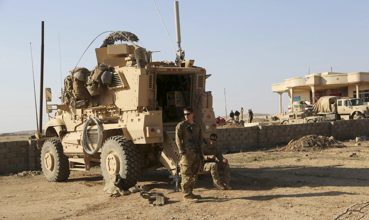 US Army soldiers stand outside their armored vehicle on a joint base with the Iraqi army, south of Mosul, Iraq. (AP/File)