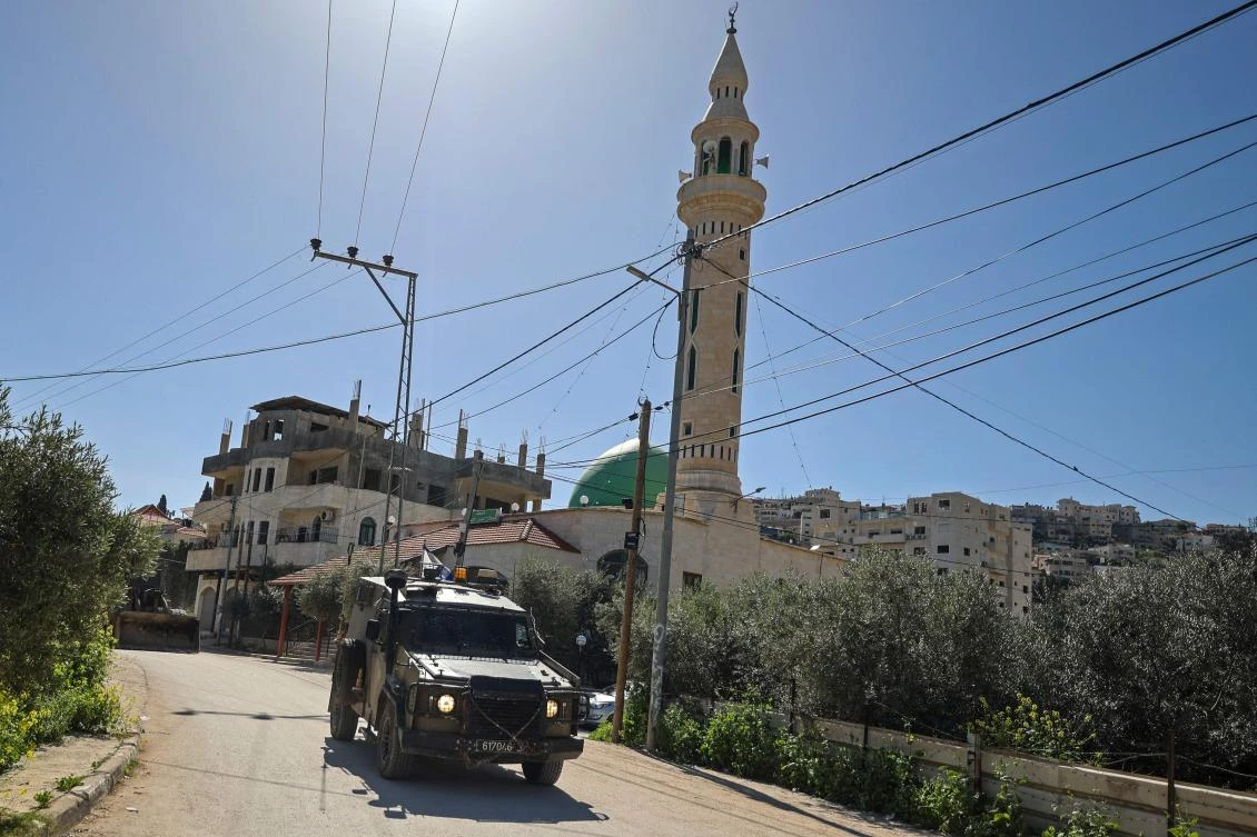 An Israeli military vehicle patrols along a street during a raid at the Jenin refugee camp area in the occupied West Bank on Mar. 12, 2024. (AFP)