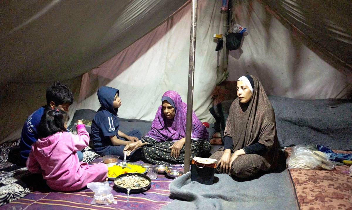 Randa Baker, right, and her family, who were displaced by the Israeli bombardment of Gaza, break their fast at a tent camp. A time of communal joy and reflection, Ramadan is overshadowed by the grim reality of a conflict that has claimed over 30,000 Palestinian lives and left vast swaths of Gaza in a shambles. (AP)