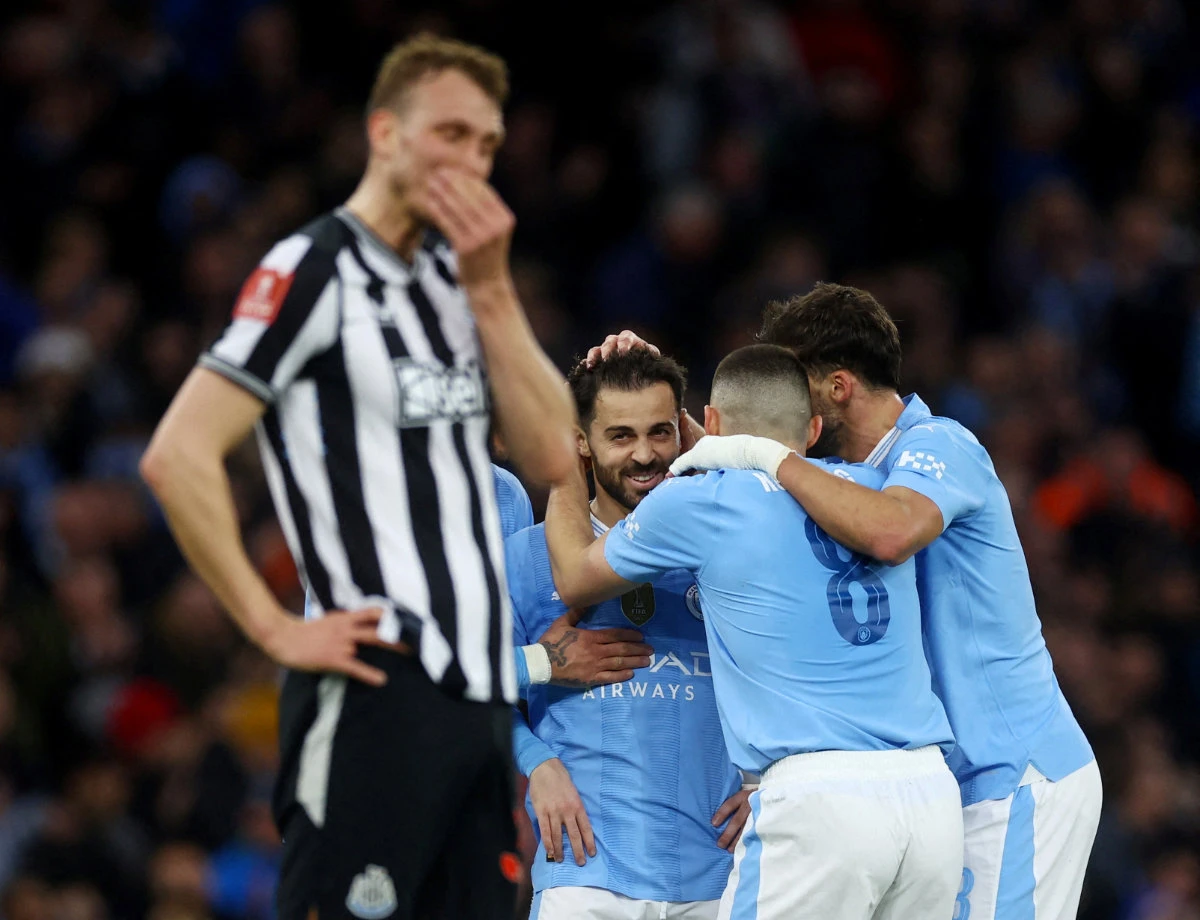 Newcastle United's Dan Burn looks dejected as Manchester City's Bernardo Silva and teammates celebrate after scoring their second goal on March 16, 2024. (Action Images via Reuters)