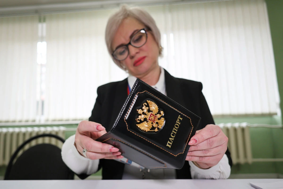 An election commission official inspects the passport of a person who came to vote at a polling station, during a presidential election in Makiivka, Russian-controlled Donetsk region, eastern Ukraine, on March 15, 2024. (AP)