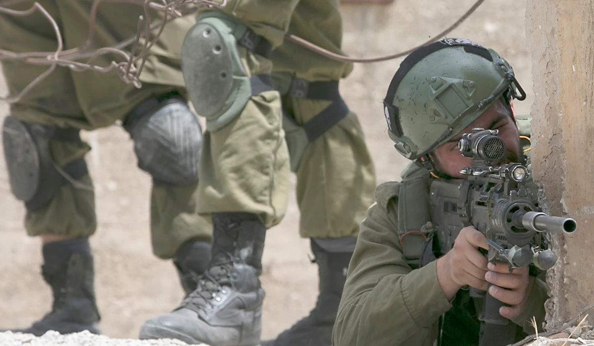 An Israeli soldier aims his gun as Israeli forces confront Palestinian protesters in Nablus, West Bank. (AFP file photo)