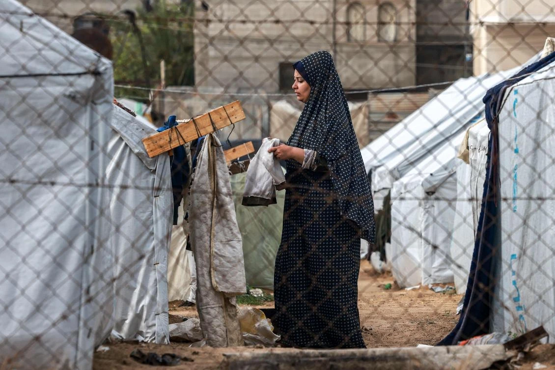 A woman hangs clothes out to dry on a laundry line outside tents housing displaced Palestinians in Rafah in the southern Gaza Strip on Mar. 19, 2024. (AFP)