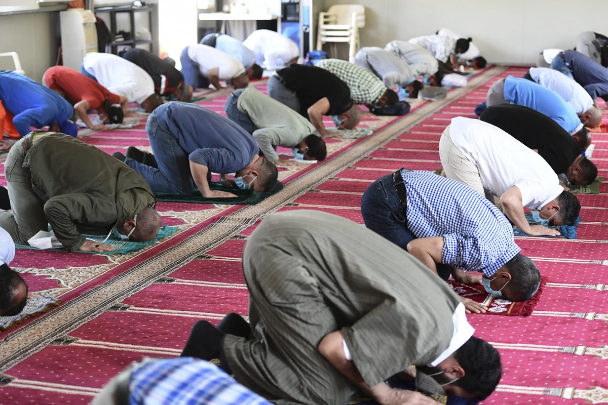 Muslims wearing protective face masks observe social distancing amid the COVID-19 coronavirus pandemic, while they attend the Friday prayer at a mosque in Milan on June 5, 2020. (AFP)