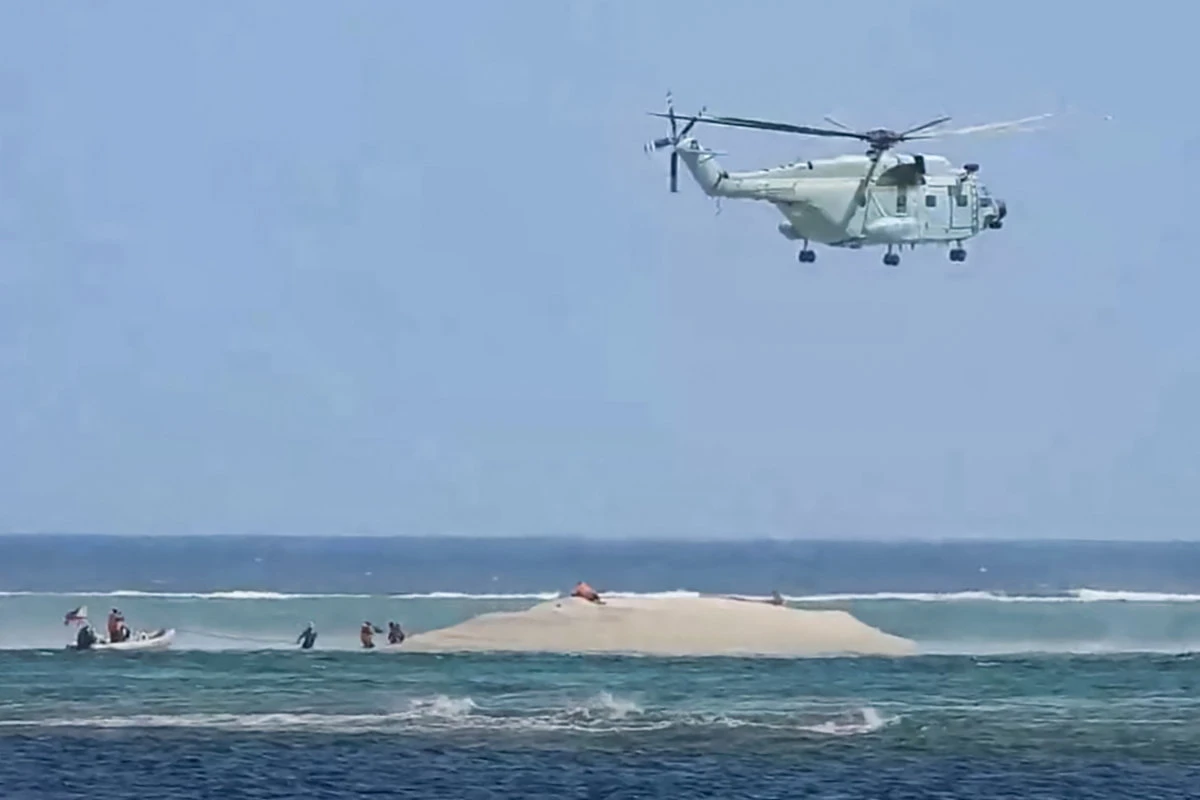 A Chinese coast guard helicopter hovers as Philippine scientists inspect a cay near the Philippine-held Thitu Island in the disputed South China Sea on March 23, 2024. (PCG/BFAR handout photo via AFP)